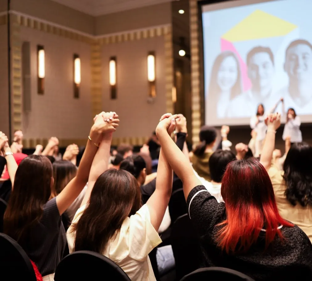 Guests raising clasped hands overhead in the awards announcement room