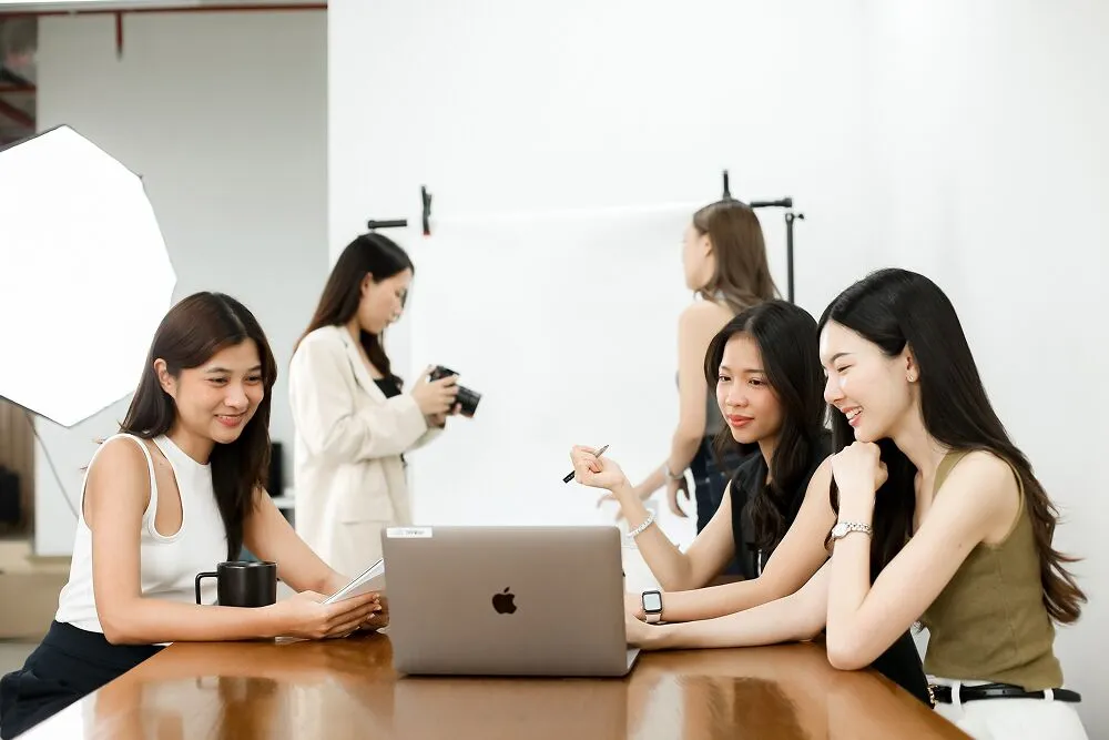 Primal team members around a laptop during a photo session in the studio